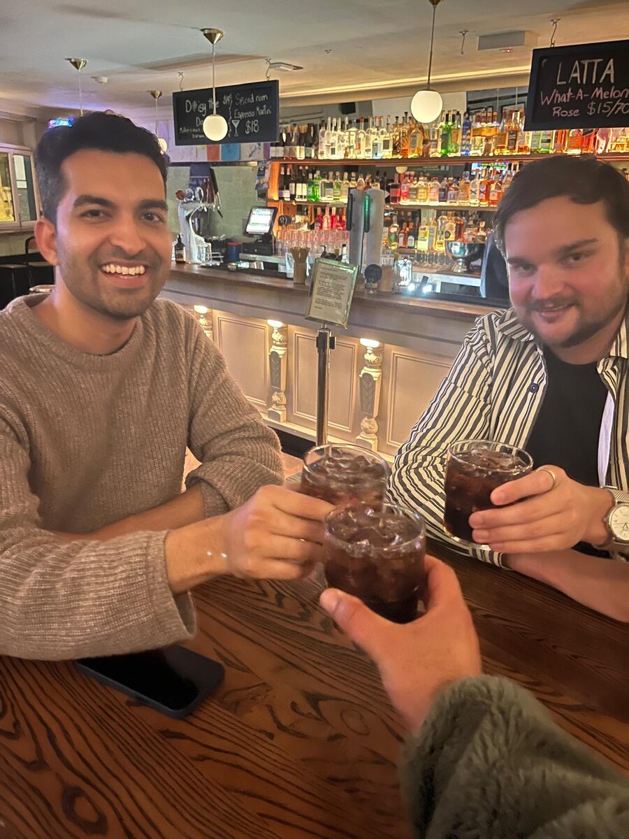 Mayuresh grinning and raising a glass with a friend at a bar